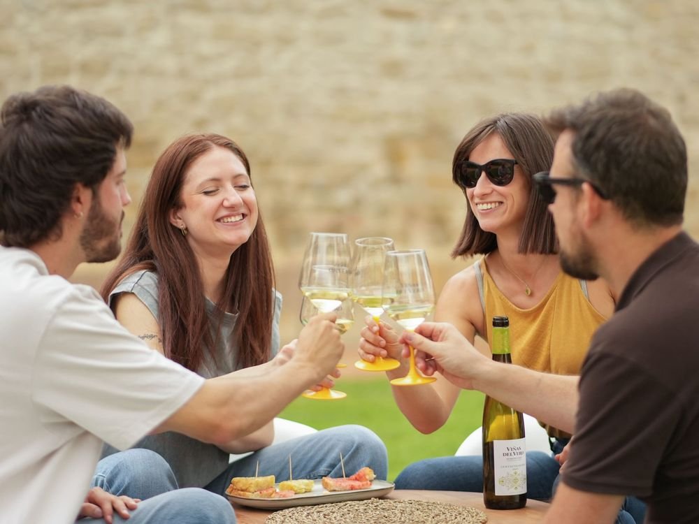 Un grupo de amigos brinda con vino blanco en una bodega